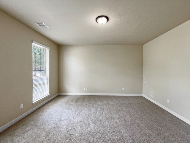 carpeted empty room with a textured ceiling