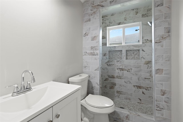 bathroom with vanity, toilet, and tiled shower