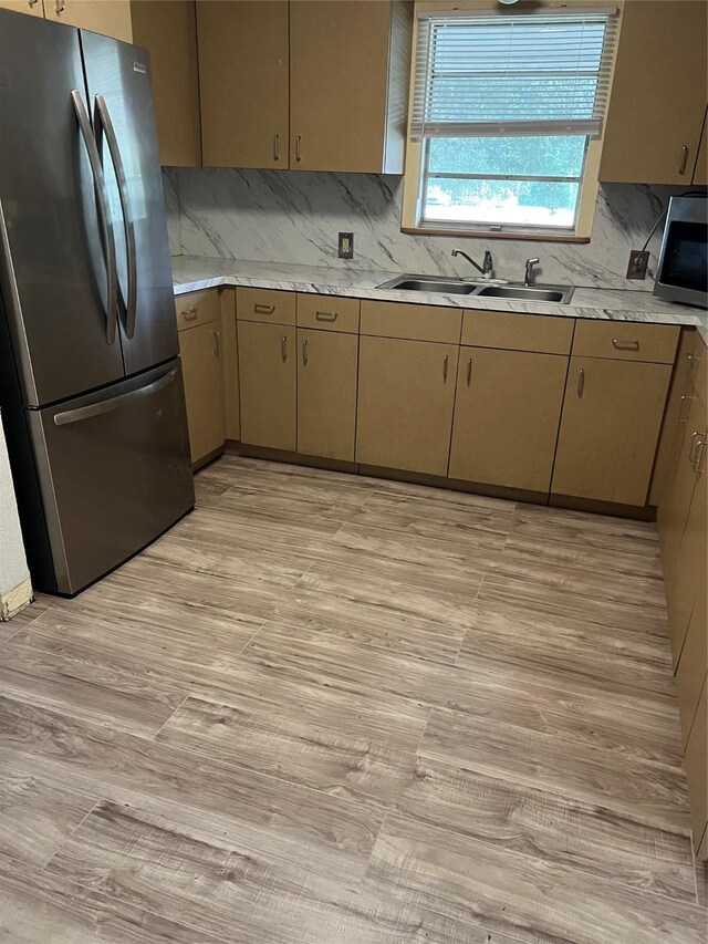 kitchen with sink, appliances with stainless steel finishes, backsplash, and light hardwood / wood-style floors