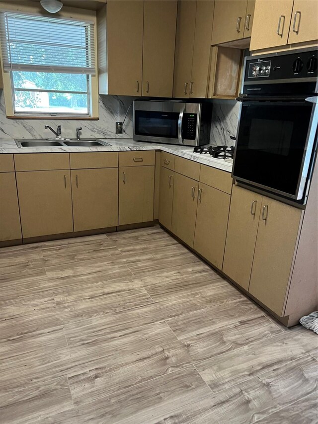 kitchen with tasteful backsplash, light wood-type flooring, black oven, white gas stovetop, and sink