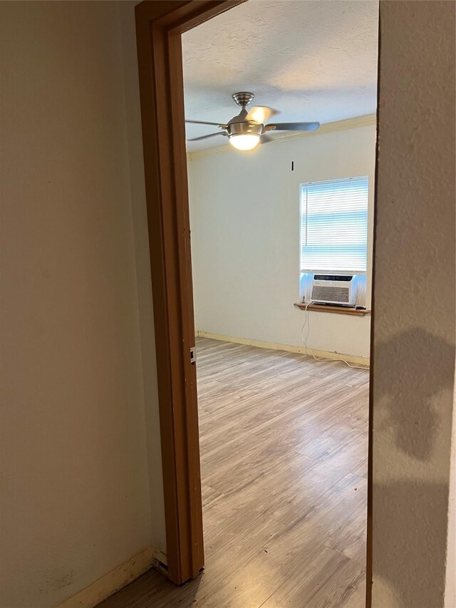 empty room featuring cooling unit, light wood-type flooring, and ceiling fan