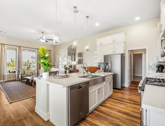 kitchen with white cabinets, hanging light fixtures, stainless steel appliances, and a kitchen island with sink