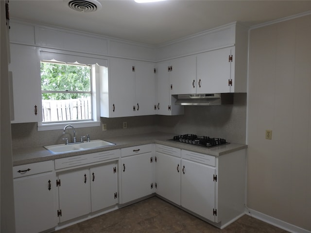 kitchen featuring gas stovetop, white cabinets, dark tile patterned flooring, decorative backsplash, and sink