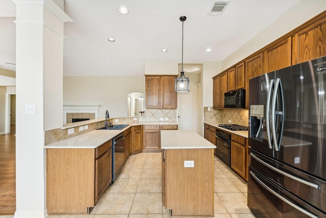 kitchen featuring tasteful backsplash, sink, black appliances, decorative light fixtures, and a center island