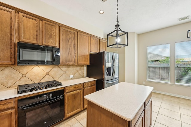 kitchen with black appliances, light tile patterned floors, tasteful backsplash, decorative light fixtures, and a kitchen island