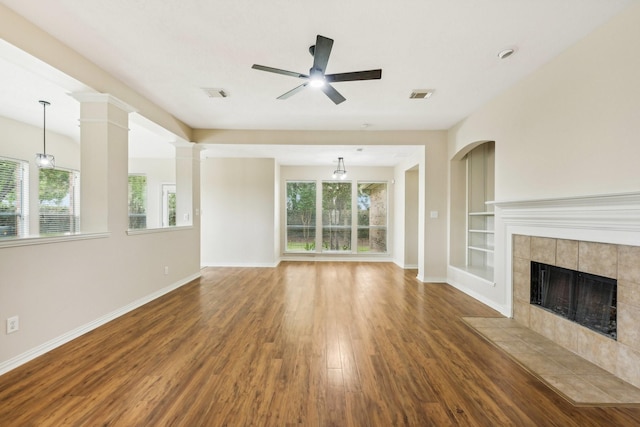 unfurnished living room with a tiled fireplace, ceiling fan, hardwood / wood-style flooring, and a wealth of natural light