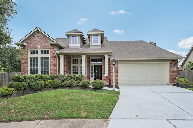 view of front of home with covered porch, a front yard, and a garage