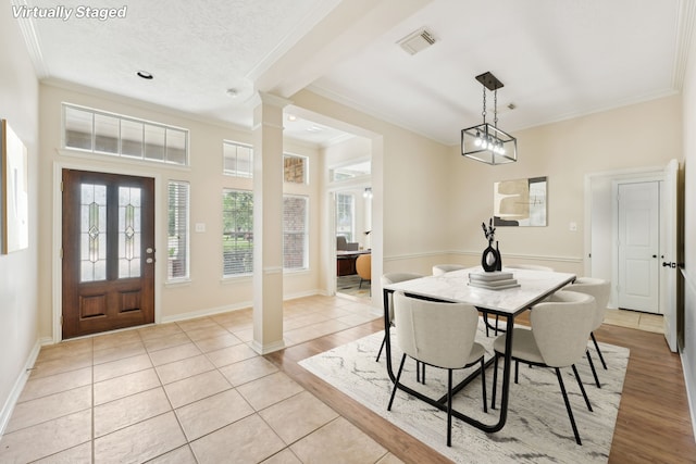 tiled dining space with ornamental molding, a textured ceiling, and an inviting chandelier