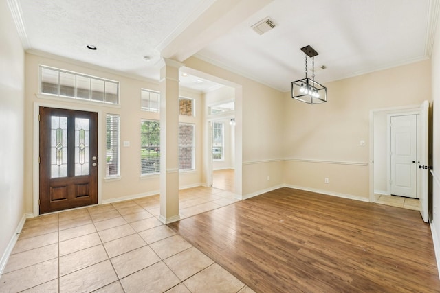 foyer entrance featuring crown molding, light tile patterned floors, a textured ceiling, and an inviting chandelier