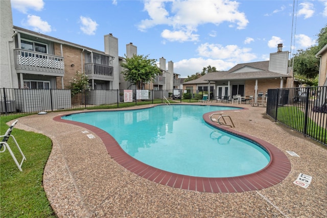 community pool with fence and a patio