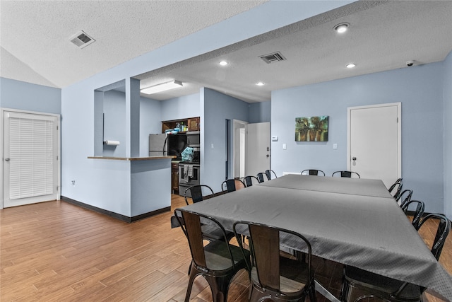 dining area featuring a textured ceiling and light hardwood / wood-style flooring