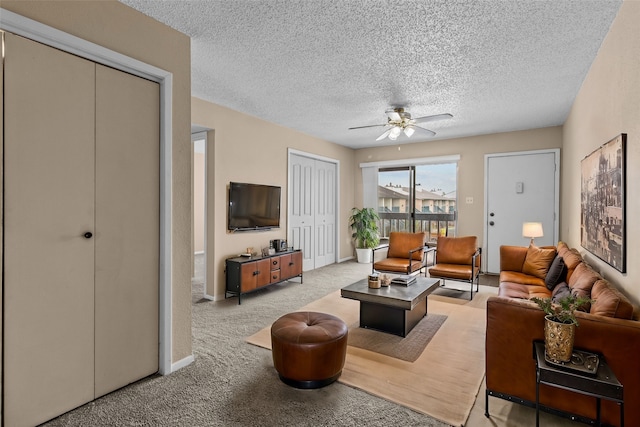 living room with a textured ceiling, light colored carpet, and ceiling fan