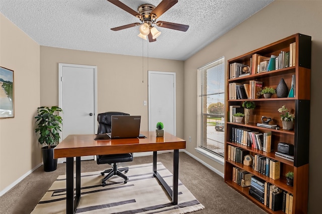 carpeted home office featuring a ceiling fan, baseboards, and a textured ceiling