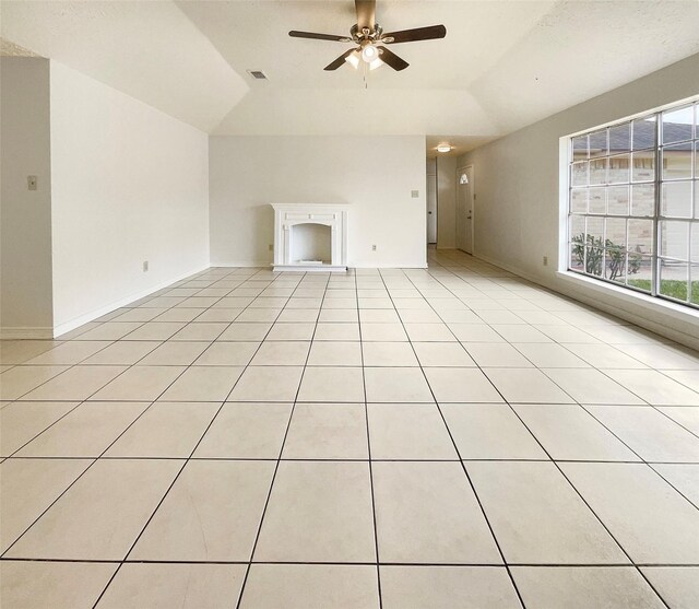 unfurnished living room with ceiling fan, plenty of natural light, light tile patterned floors, and a tray ceiling