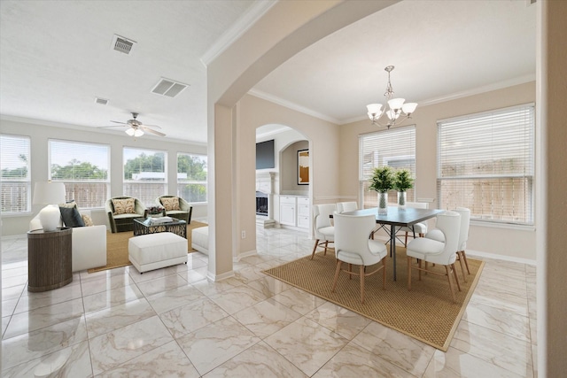 dining room featuring a fireplace, a wealth of natural light, crown molding, and ceiling fan with notable chandelier