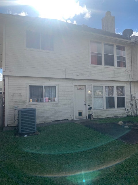 view of front facade with cooling unit and a front lawn