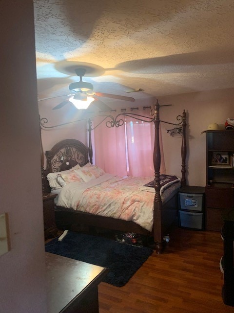 bedroom featuring a textured ceiling, ceiling fan, and dark hardwood / wood-style floors