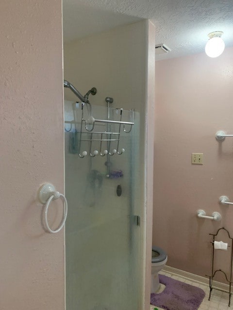 bathroom with tile patterned flooring, toilet, and a textured ceiling