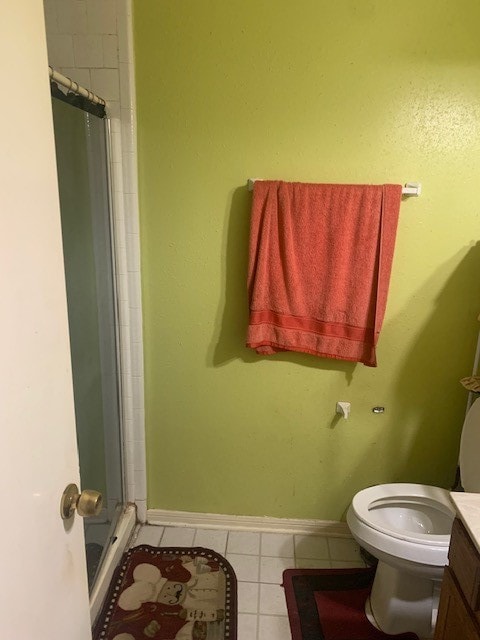 bathroom featuring tile patterned flooring, toilet, vanity, and an enclosed shower