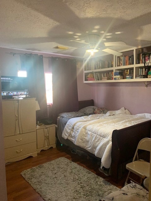 bedroom featuring ceiling fan, a textured ceiling, and hardwood / wood-style flooring