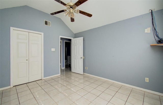 unfurnished bedroom featuring ceiling fan, a closet, light tile patterned floors, and lofted ceiling