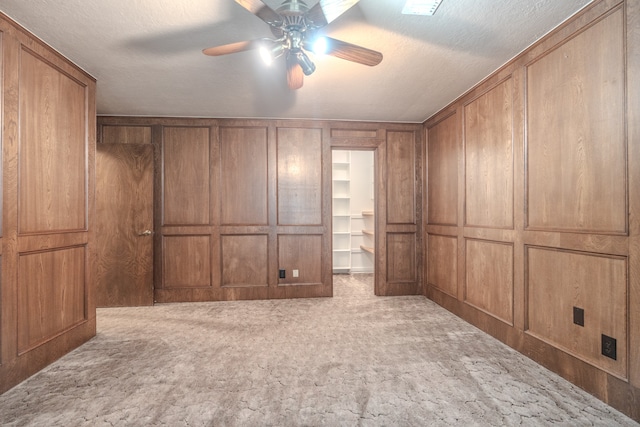 interior space featuring wood walls, carpet floors, and ceiling fan