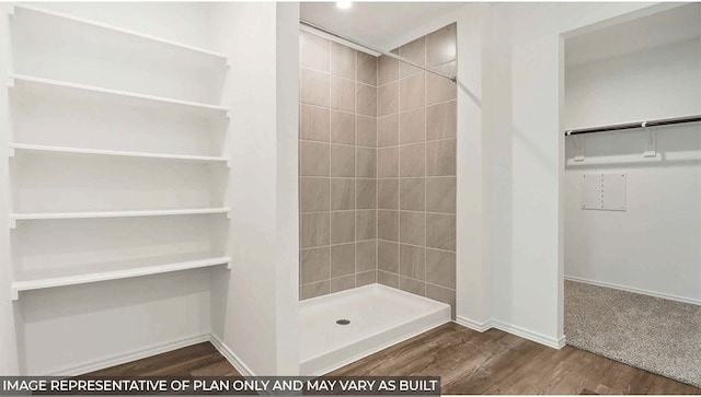 bathroom with a tile shower and hardwood / wood-style flooring