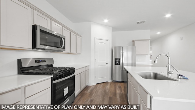 kitchen featuring stainless steel appliances, dark wood-type flooring, sink, white cabinetry, and an island with sink