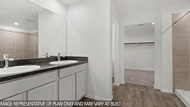 bathroom with tiled shower, hardwood / wood-style floors, and vanity