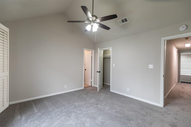 unfurnished bedroom featuring carpet floors, ceiling fan, a walk in closet, a closet, and high vaulted ceiling