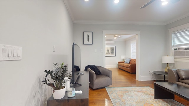 living room with wood-type flooring, crown molding, and ceiling fan