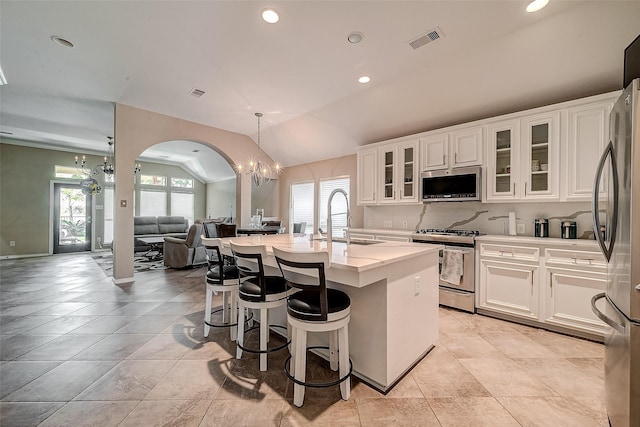 kitchen featuring sink, appliances with stainless steel finishes, white cabinetry, a center island with sink, and a chandelier