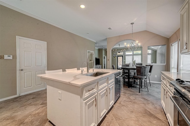 kitchen with lofted ceiling, sink, decorative light fixtures, an island with sink, and stainless steel appliances