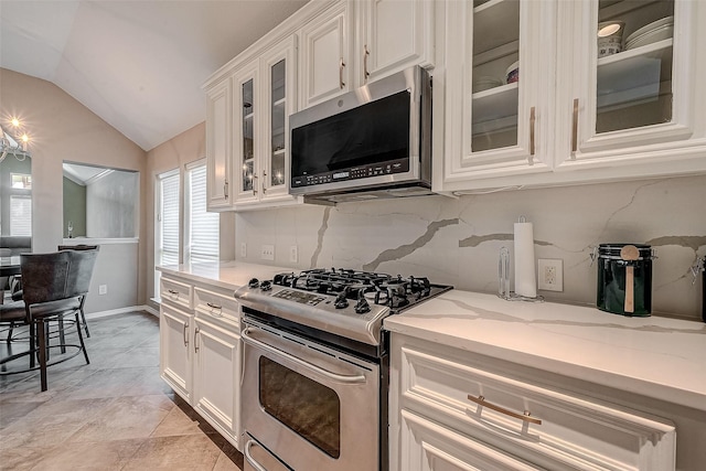 kitchen featuring vaulted ceiling, appliances with stainless steel finishes, white cabinets, and backsplash