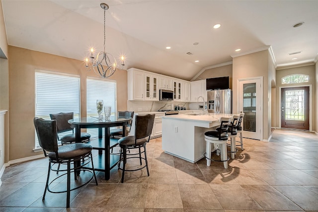 kitchen with a breakfast bar, appliances with stainless steel finishes, white cabinetry, hanging light fixtures, and a center island