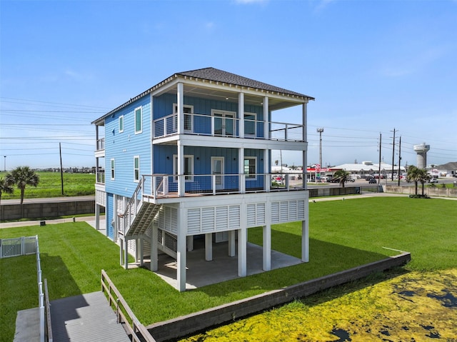 back of property with a balcony, a patio area, and a yard