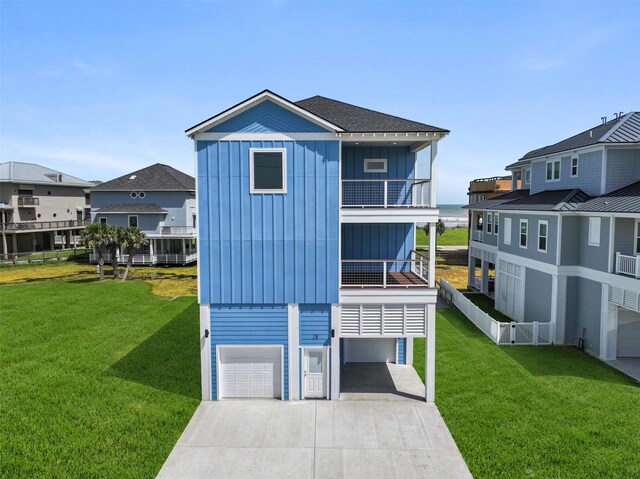 rear view of property featuring a balcony, a garage, and a yard