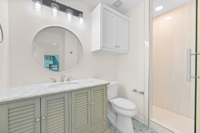 bathroom with vanity, a tile shower, tile patterned floors, and toilet