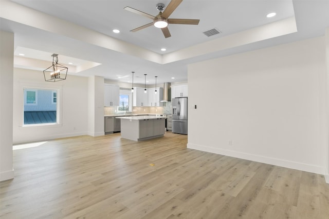 kitchen with a kitchen island, stainless steel appliances, a tray ceiling, and pendant lighting