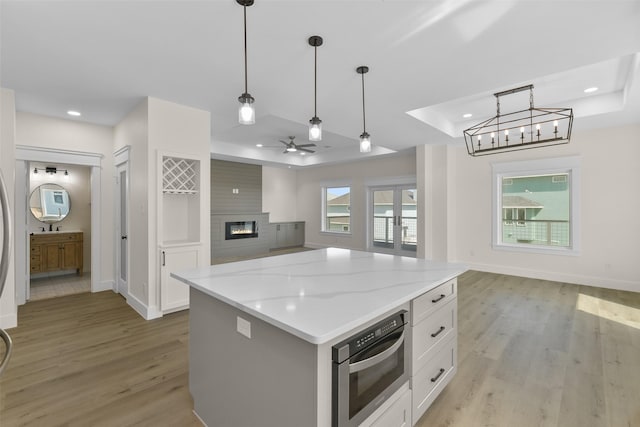 kitchen featuring stainless steel oven, a kitchen island, white cabinetry, and pendant lighting