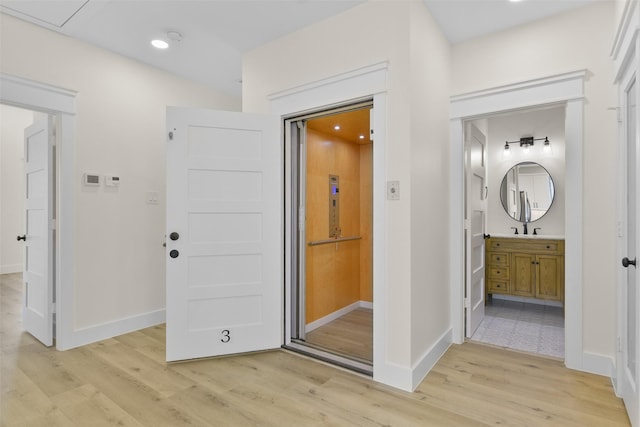 corridor with sink and light hardwood / wood-style flooring