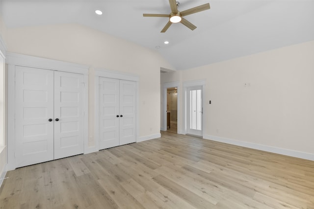 unfurnished bedroom with ceiling fan, light hardwood / wood-style floors, two closets, and lofted ceiling