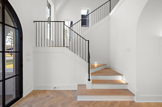 stairs featuring arched walkways, baseboards, and a high ceiling