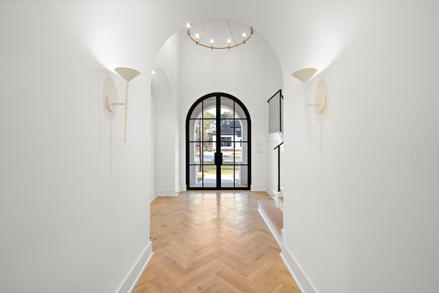 hall with arched walkways, french doors, a notable chandelier, and baseboards