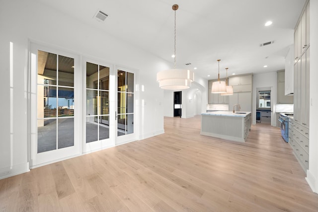 kitchen with stainless steel range, light countertops, visible vents, a sink, and light wood-type flooring