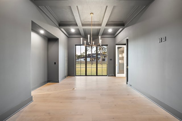 unfurnished dining area with baseboards, light wood-style floors, coffered ceiling, and a notable chandelier