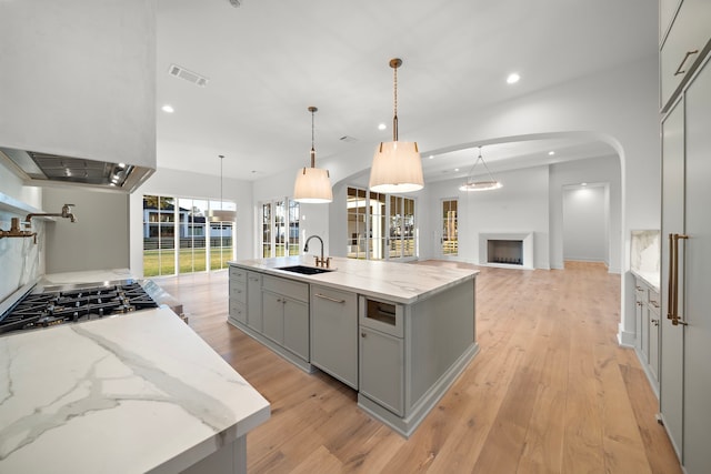 kitchen featuring light wood-style flooring, a fireplace, gray cabinets, and a sink