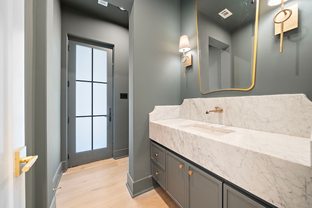 bathroom featuring baseboards, visible vents, wood finished floors, and vanity