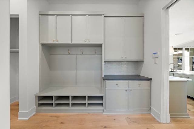 mudroom featuring light wood-type flooring, a sink, and baseboards