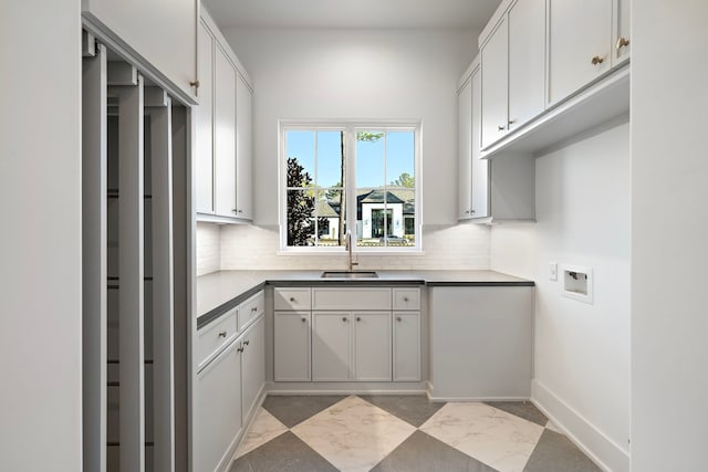 interior space featuring dark countertops, a sink, backsplash, and baseboards